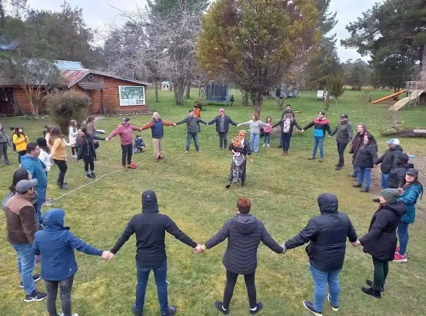 Docentes formando un círculo tomados de la mano en el patio de un colegio
