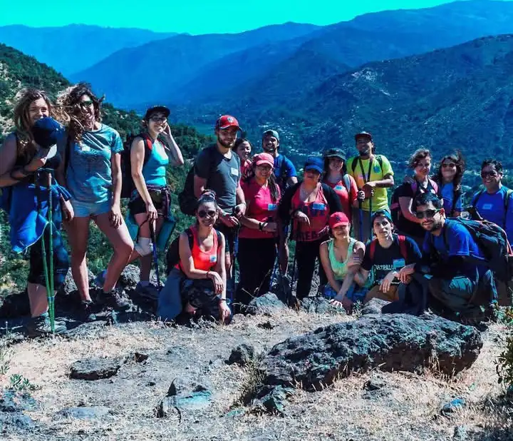 Grupo de trekking en una cumbre con la cordillera de fondo